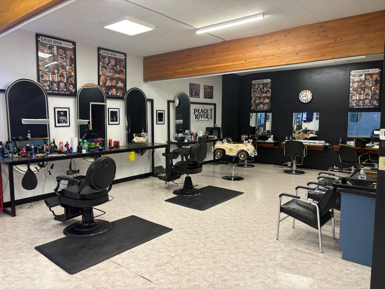 A wide view of the barber stations, waiting chairs and kids car chair